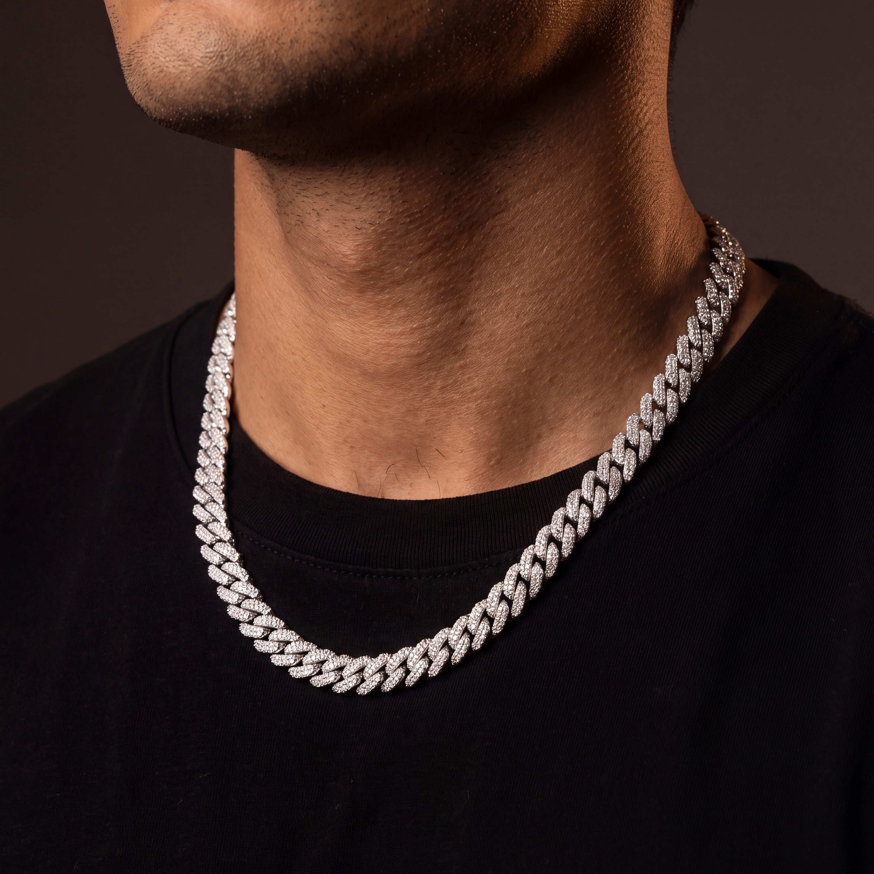 Iced Miami Cuban link chain in white gold tone worn on a man's neck over a black t-shirt